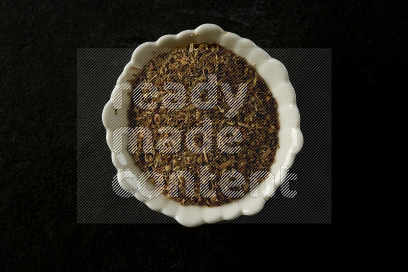 white ceramic round sauce bowl filled with herbs on grey textured countertop