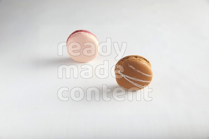 45º Shot of of two assorted Brown Irish Cream, and Pink Litchi Raspberry macarons on white background