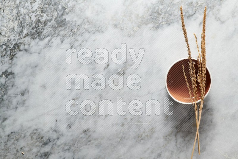 Wheat stalks on Brown Pottery Bowl on grey marble flooring, Top view