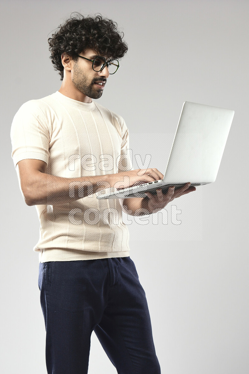 A man wearing casual standing and working on a laptop on white background