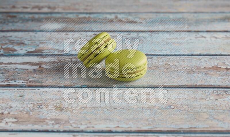 45º Shot of two Green Pistachio macarons on light blue wooden background