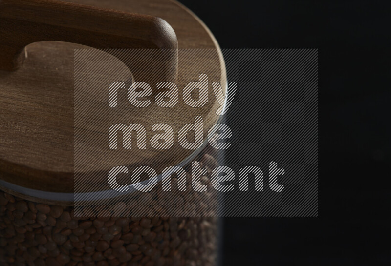 عدس بني في وعاء زجاجي على خلفية سوداء