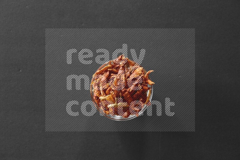 A glass bowl full of dried red chili peppers on black flooring