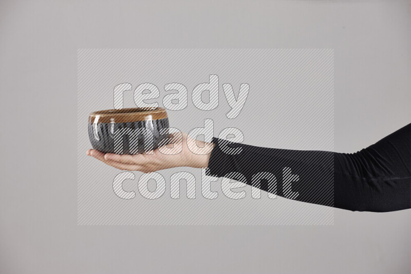 A woman in black abaya holding different pottery essentials in different positions
