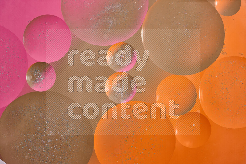 لقطات مقربة لفقاعات من الزيت على سطح الماء باللون البني والبرتقالي والوردي