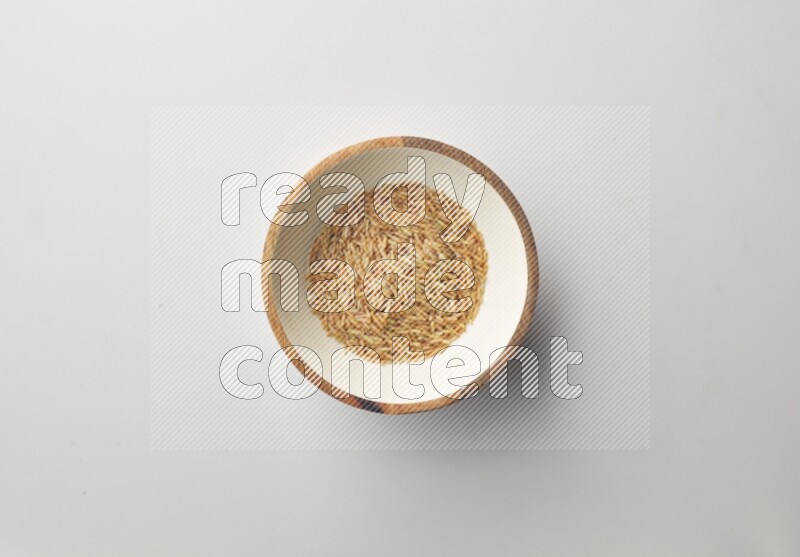 Top-view shot of long grain brown rice in a container on white background