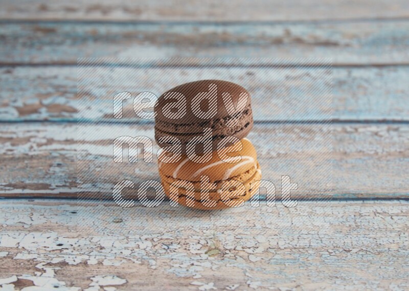45º Shot of of two assorted Brown Irish Cream, and Brown Dark Chocolate macarons on light blue background