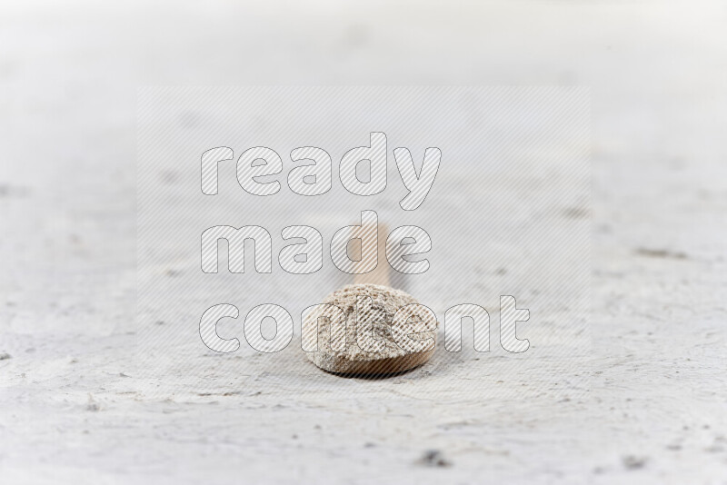 A wooden spoon full of onion powder on white background