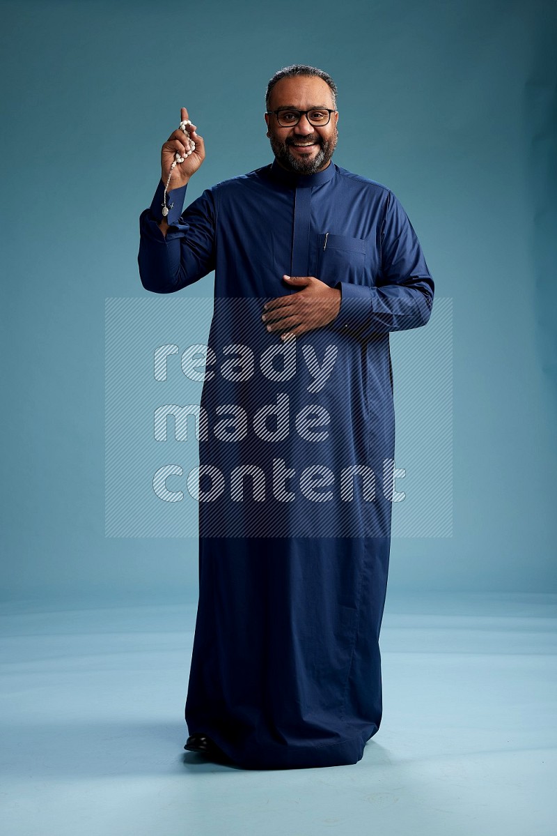 Saudi Man without shimag Standing Interacting with the camera on blue background