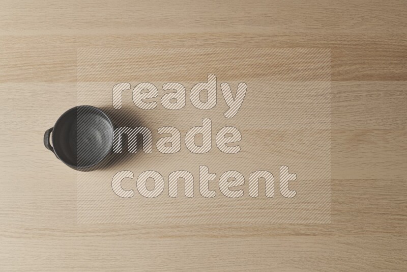 وعاء فخاري أسود على خلفية خشبية فاتحة