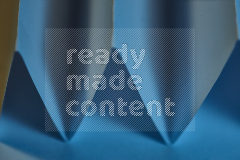 صورة مجردة مقربة تظهر طيات ورقية هندسية حادة بتدرجات اللون الأزرق