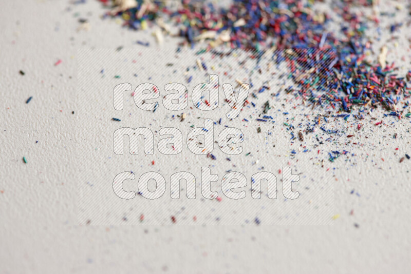 This image showcases a vibrant multicolored pencil shavings scattered on grey background