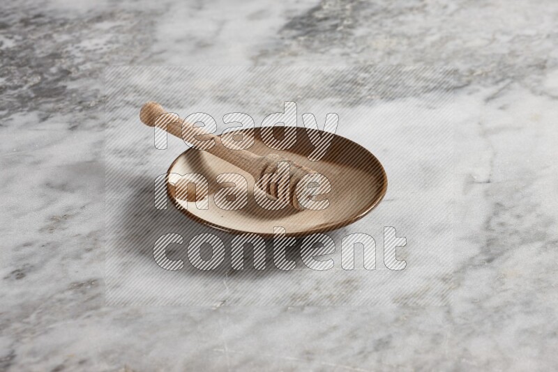 Multicolored pottery plate with wooden honey dipper in it on grey marble background