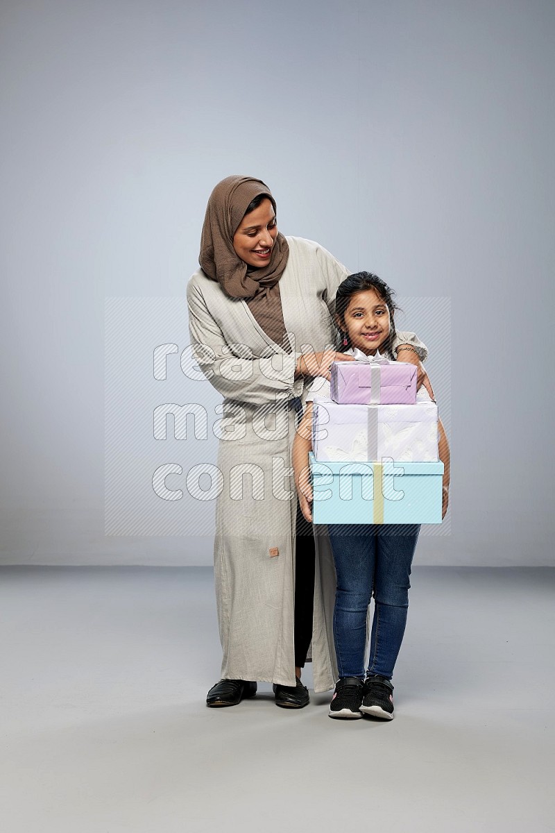 A girl giving a gift to her mother on gray background