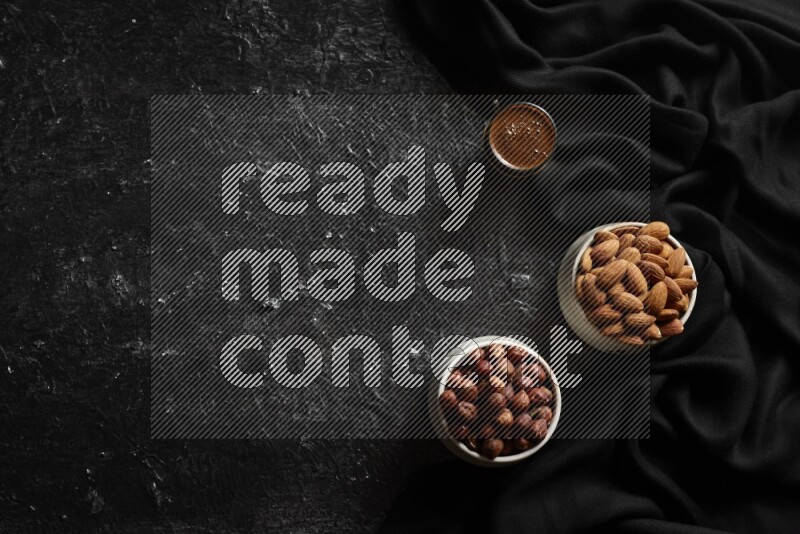 مكسرات في أطباق فخارية مع القهوة علي خلفية سوداء خشبية