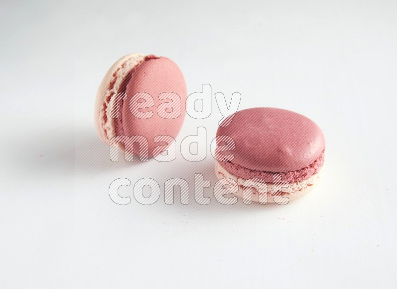 45º Shot of two Pink Litchi Raspberry macarons on white background