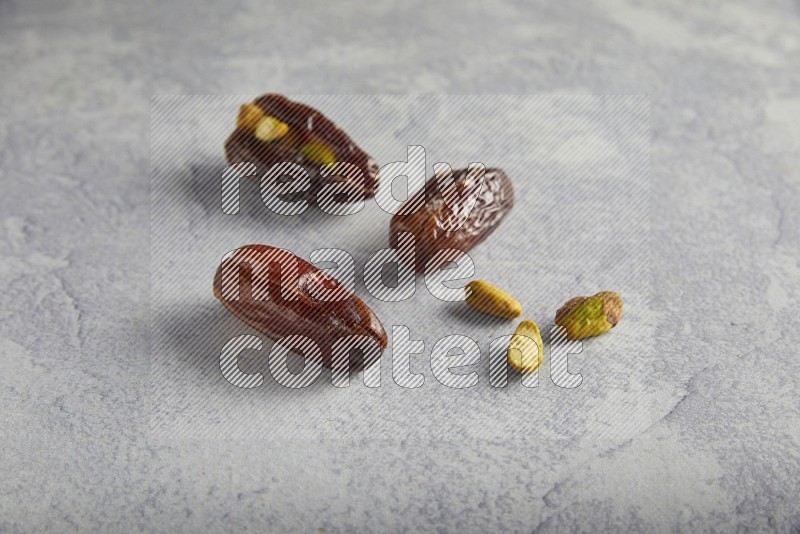 dates and unroasted pistachios on a light grey background