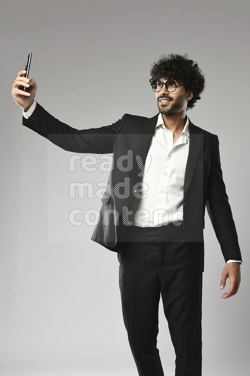 A man wearing formal standing and taking a selfie on white background