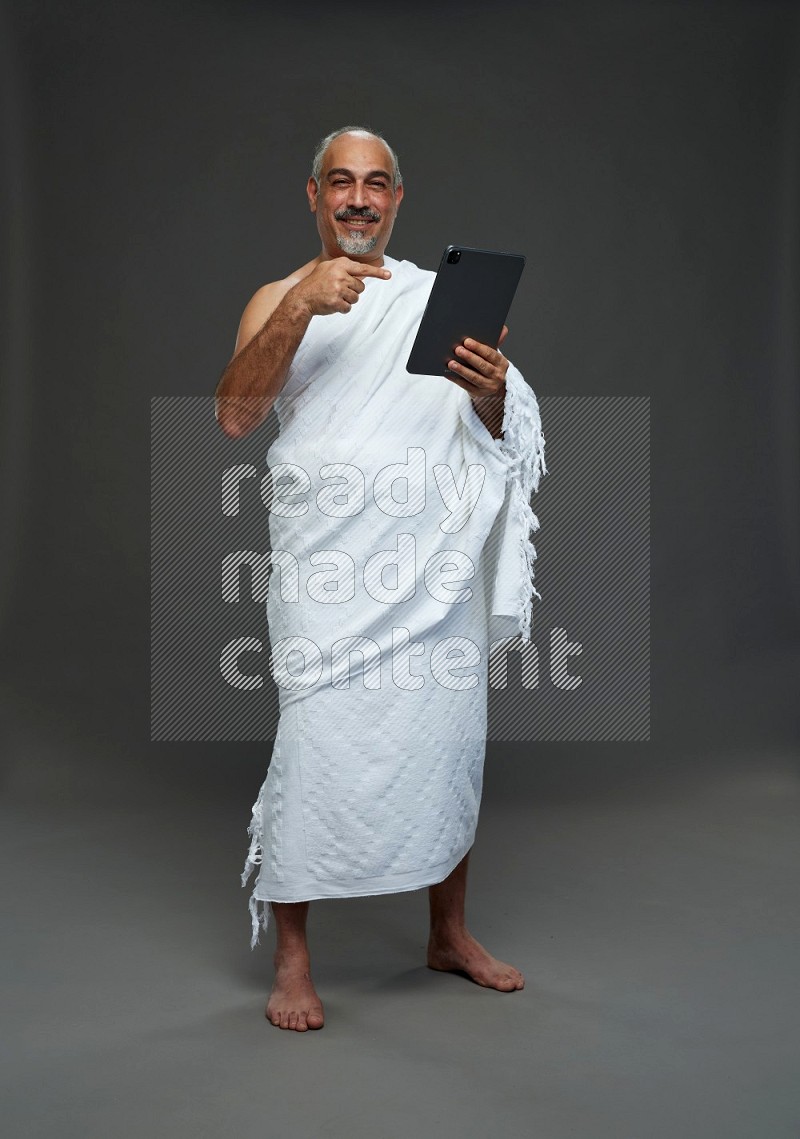 A man wearing Ehram Standing working on tablet on gray background