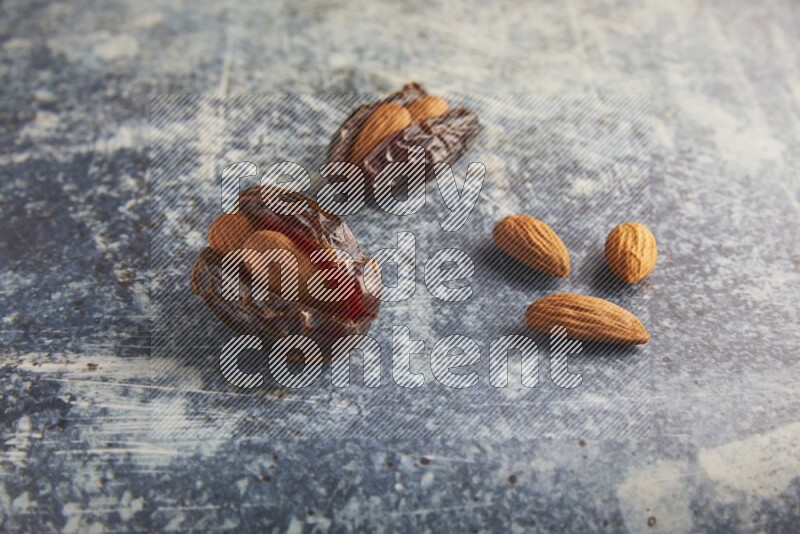 two almond stuffed madjoul dates on a rustic blue background