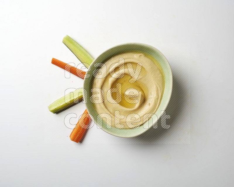Hummus in a green plate garnished with olive oil on a white background