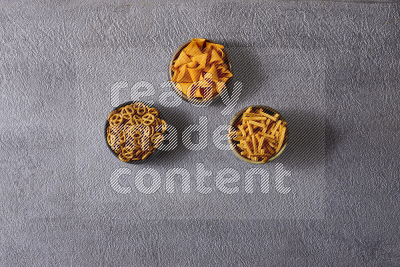 Assorted snacks in pottery bowls on grey background