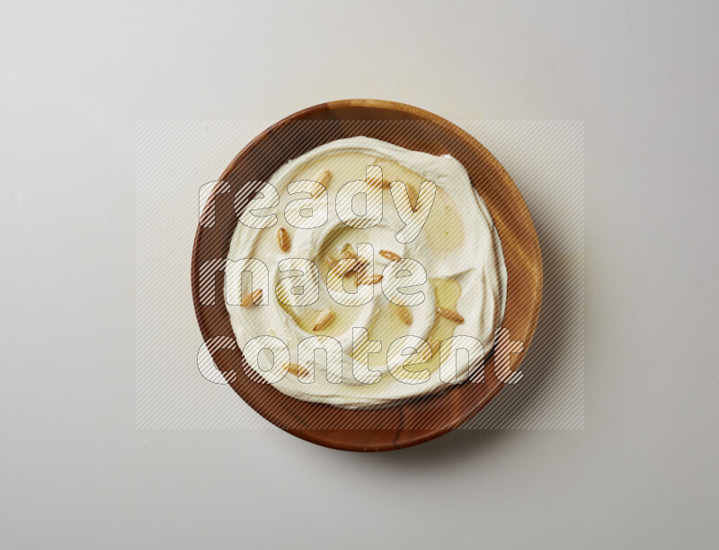 Lebnah garnished with pine nuts in a wooden plate on a white background