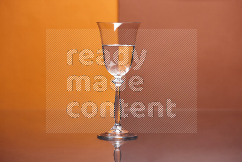 The image features a clear glassware filled with water, set against orange and dark orange background