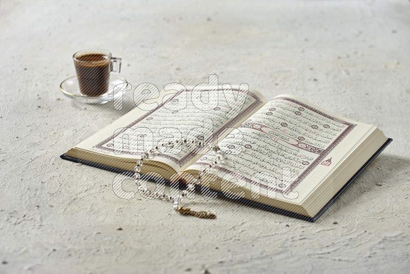 Quran with dates, prayer beads and different drinks on textured white background