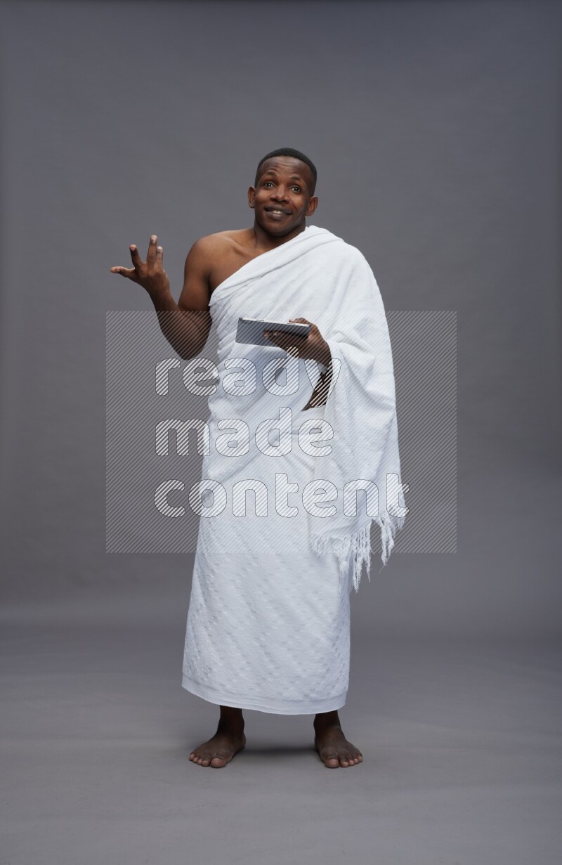 A man wearing Ehram Standing working on tablet on gray background