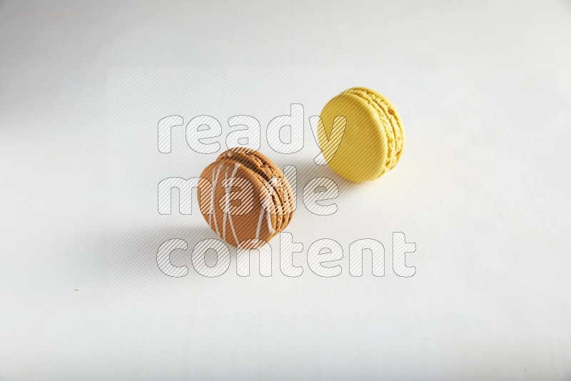 45º Shot of of two assorted Brown Irish Cream, and Yellow Lemon macarons on white background