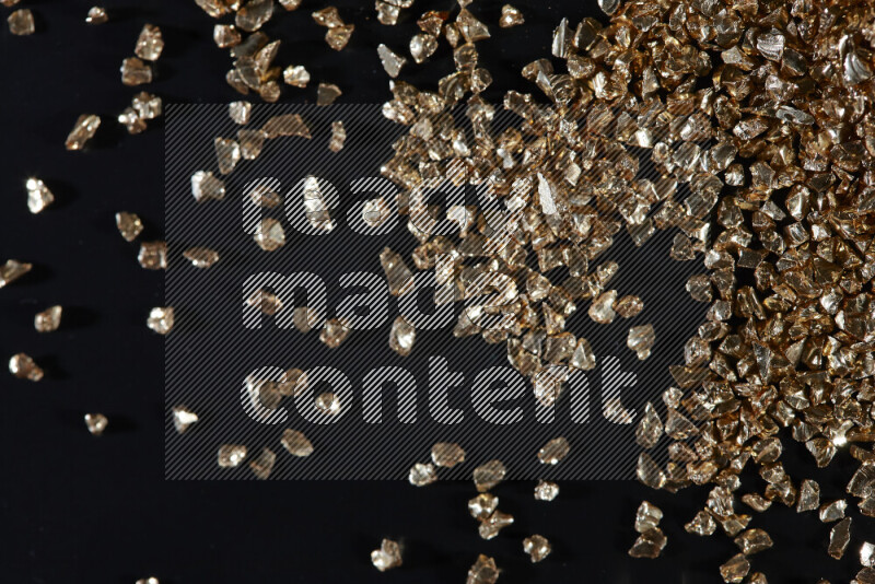 Gold shimmering fragments of glass scattered on a black background
