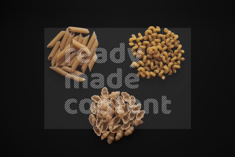Different pasta types in bunches on black background