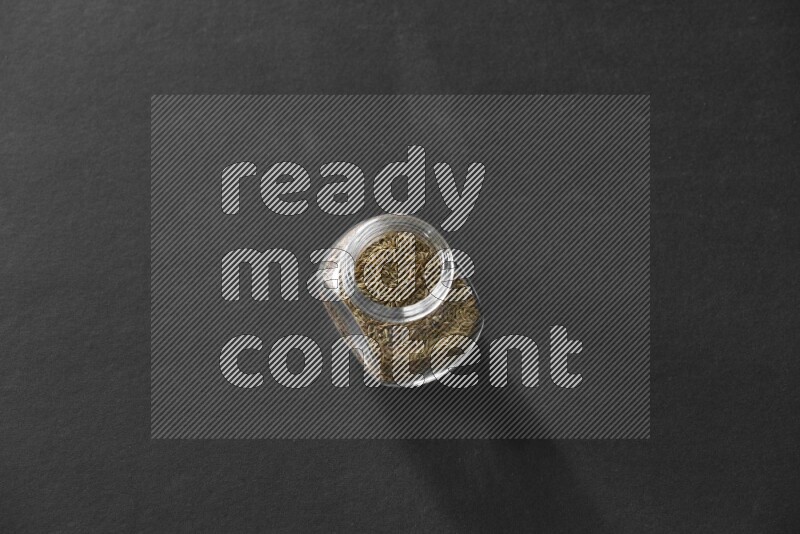 كمون في وعاء زجاجي علي خلفية سوداء
