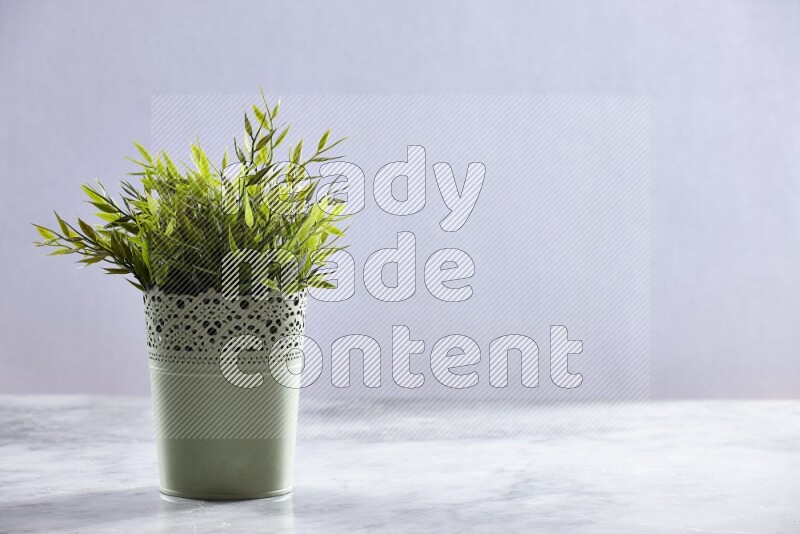 Artificial plant in green decorative pot on grey marble background