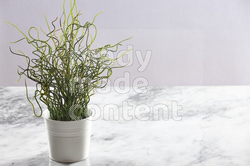 Green artificial plant in white pot on light grey marble background