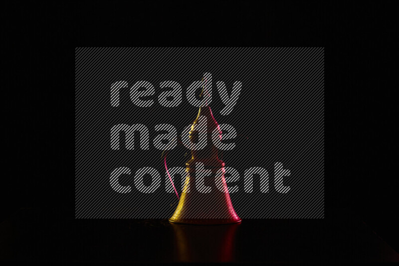 A turkish coffee pot with colored rim light against black background