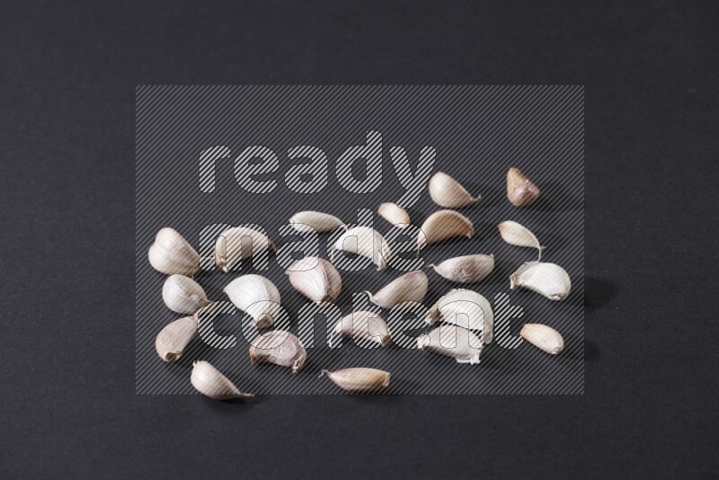 بعض فصوص الثوم متناثرة على أرضية سوداء