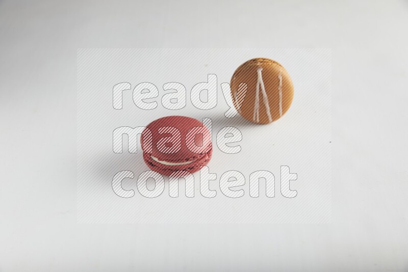 45º Shot of of two assorted Brown Irish Cream, and Red Velvet macarons on white background