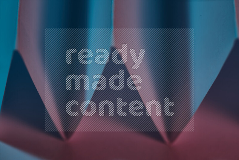A close-up abstract image showing sharp geometric paper folds in blue and red gradients