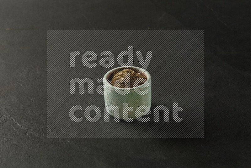 multi color round sauce bowl filled with herbs on grey textured countertop