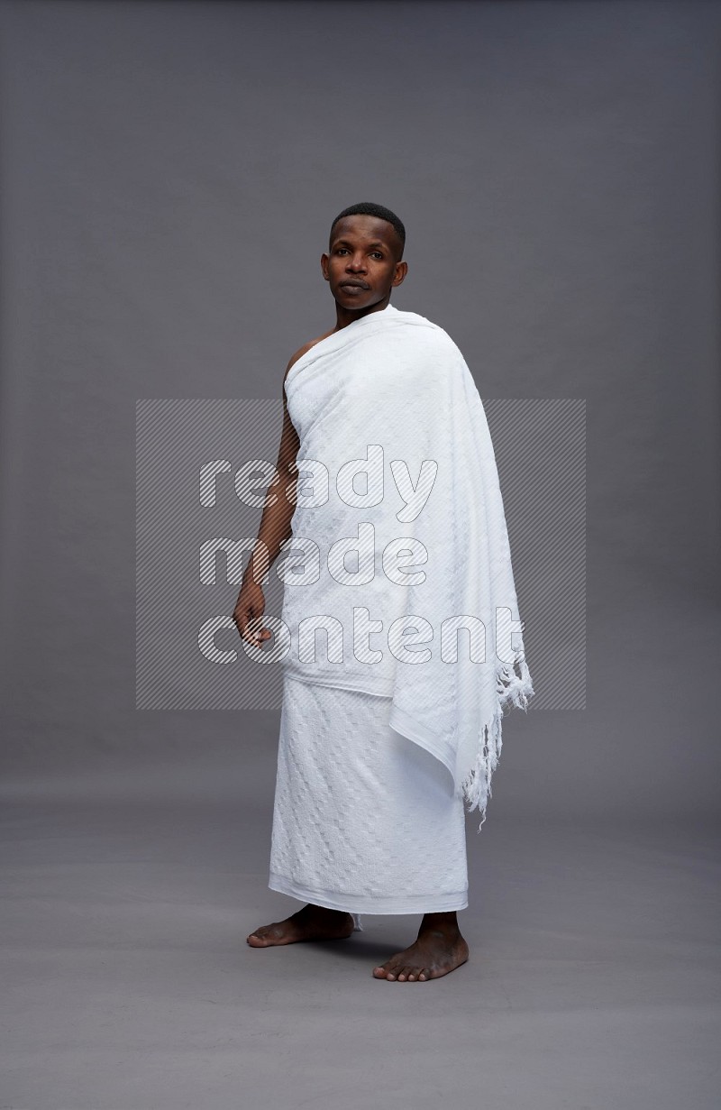 A man wearing Ehram Standing Interacting with the camera on gray background