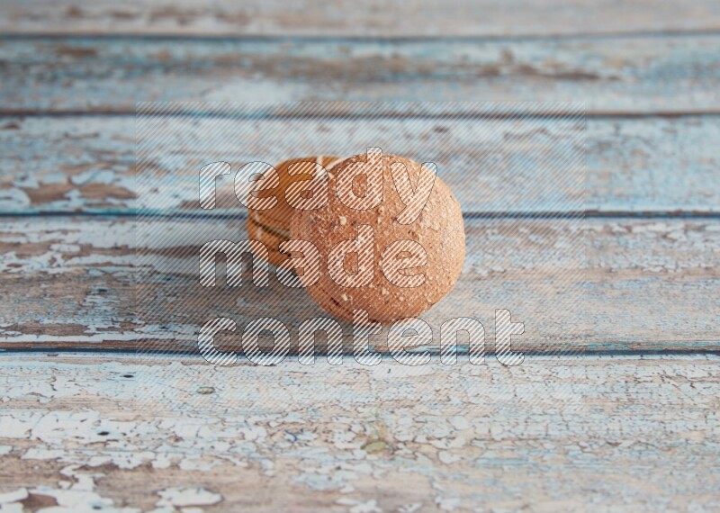 45º Shot of of two assorted Brown Irish Cream, and Brown Hazelnuts macarons  on light blue background