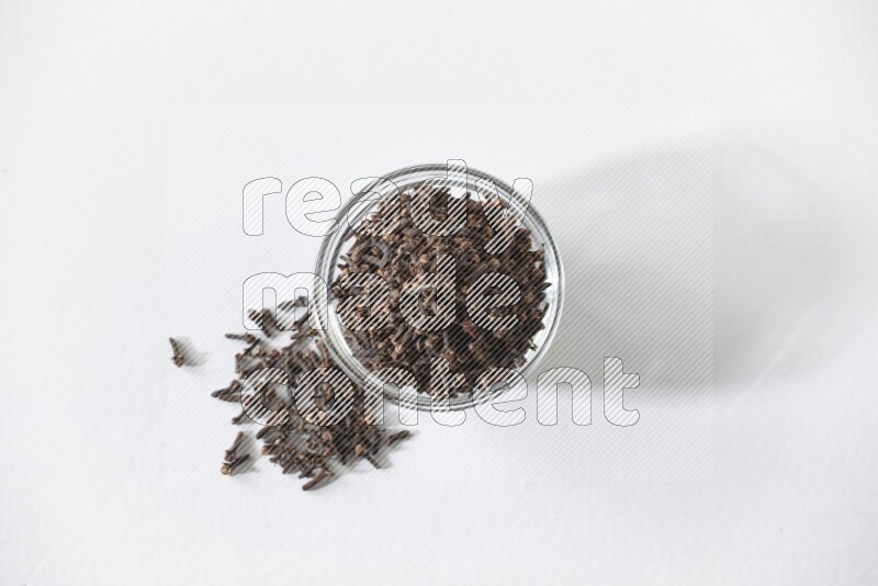 A glass bowl full of cloves on a white flooring