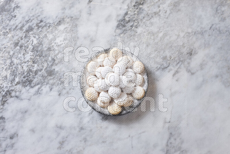 كحك في صحن فخار أسود على خلفية رخام رمادي