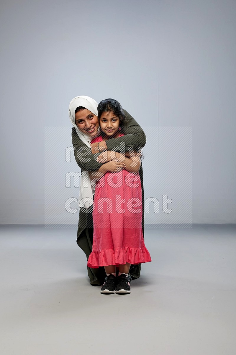 A girl and her mother interacting with the camera on gray background