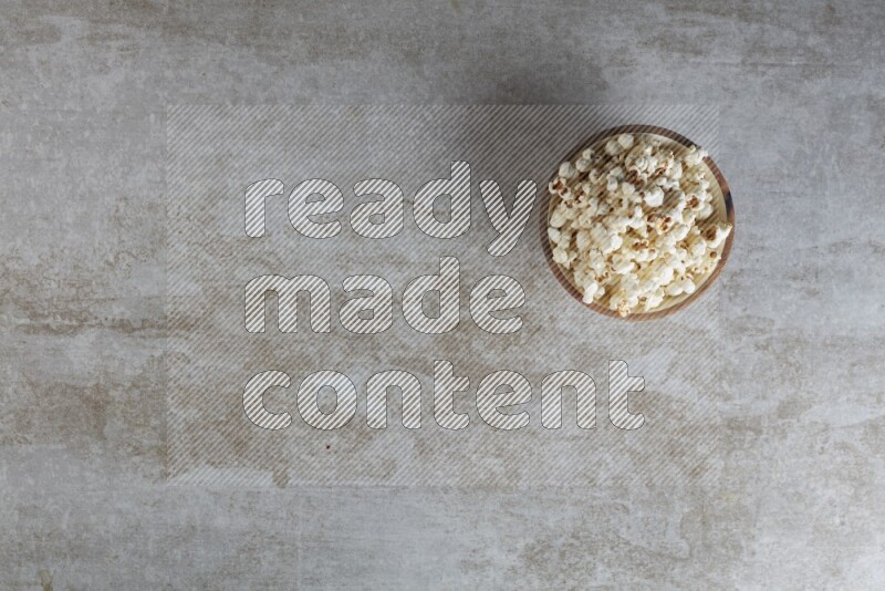 popcorn in wooden bowl on a grey textured countertop