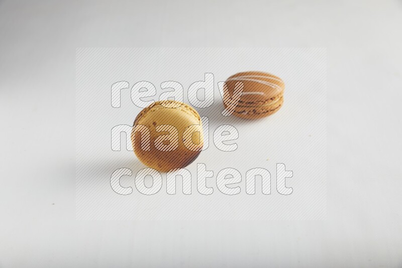 45º Shot of of two assorted Brown Irish Cream, and Yellow Crème Brulée macarons on white background