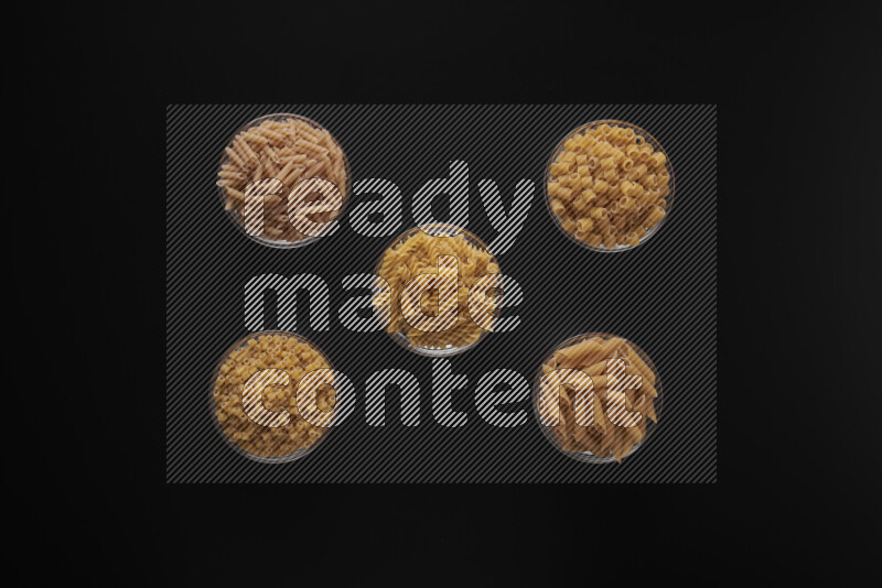 أنواع مختلفة من المعكرونة في أوعية زجاجية علي خلفية سوداء