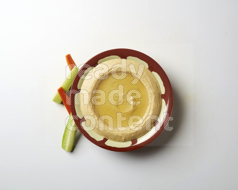 Hummus in a traditional plate garnished with olive oil on a white background